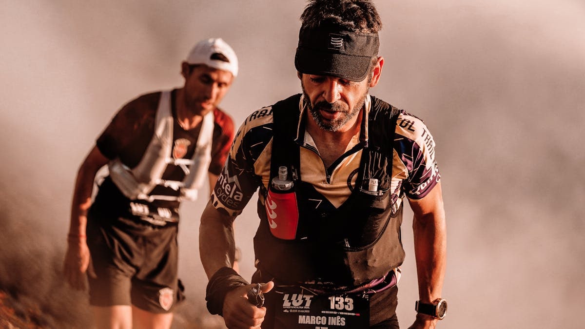 Two male athletes competing in a challenging outdoor trail race with determination.